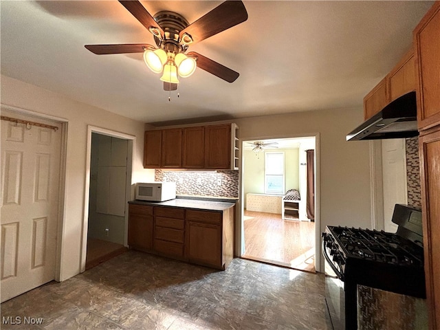 kitchen with black gas range oven, backsplash, ceiling fan, and dark hardwood / wood-style floors