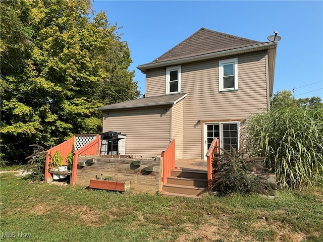 back of property featuring a deck and a lawn