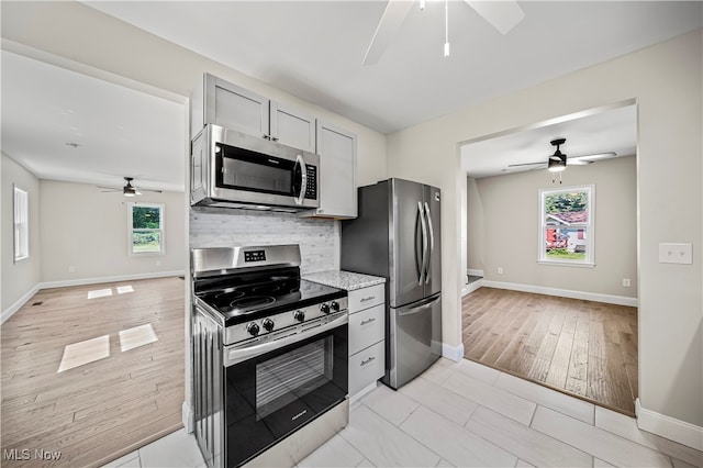 kitchen featuring ceiling fan, stainless steel appliances, tasteful backsplash, and light hardwood / wood-style flooring