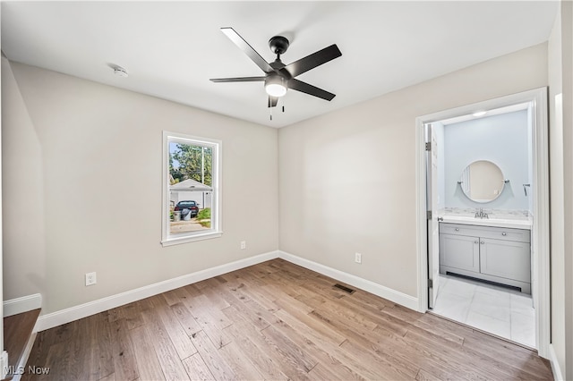 empty room with light wood-type flooring, sink, and ceiling fan