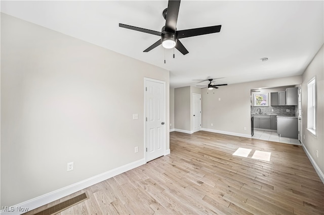 unfurnished living room with light wood-type flooring, sink, and ceiling fan