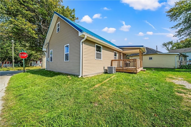 rear view of property with a lawn, cooling unit, and a wooden deck