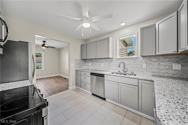 kitchen with sink, gray cabinetry, stainless steel appliances, light stone countertops, and ceiling fan