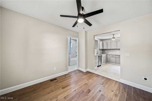 unfurnished living room with ceiling fan, sink, and light hardwood / wood-style floors