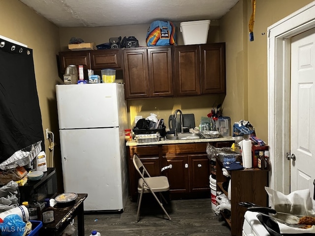 kitchen featuring a textured ceiling, dark hardwood / wood-style flooring, sink, white refrigerator, and dark brown cabinetry