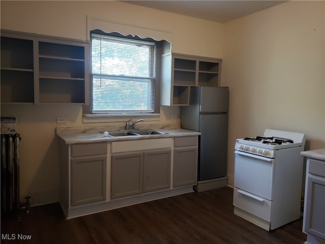 kitchen featuring dark wood-type flooring, refrigerator, white gas stove, and sink