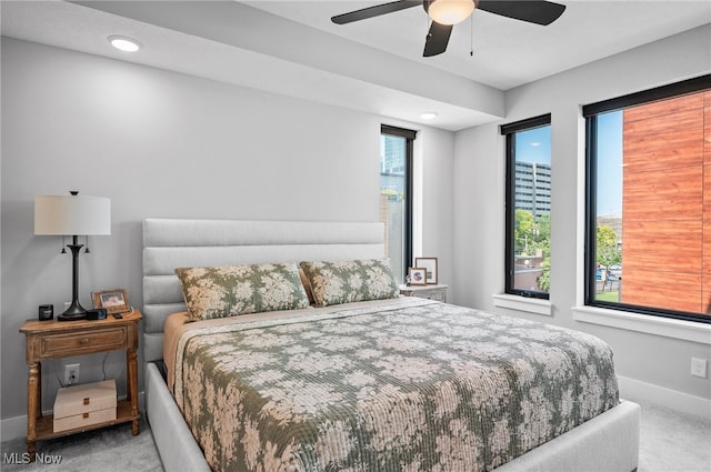 carpeted bedroom featuring multiple windows and ceiling fan