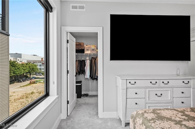 carpeted bedroom featuring multiple windows, a walk in closet, and a closet