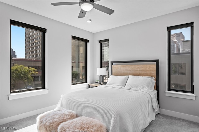 carpeted bedroom featuring multiple windows and ceiling fan