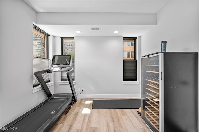 workout area featuring light hardwood / wood-style floors and beverage cooler