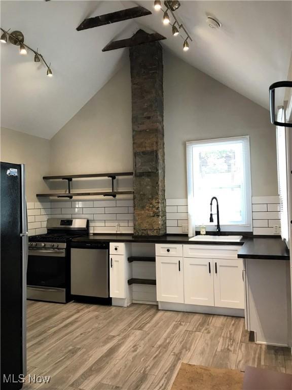 kitchen featuring light hardwood / wood-style flooring, appliances with stainless steel finishes, sink, decorative backsplash, and white cabinets