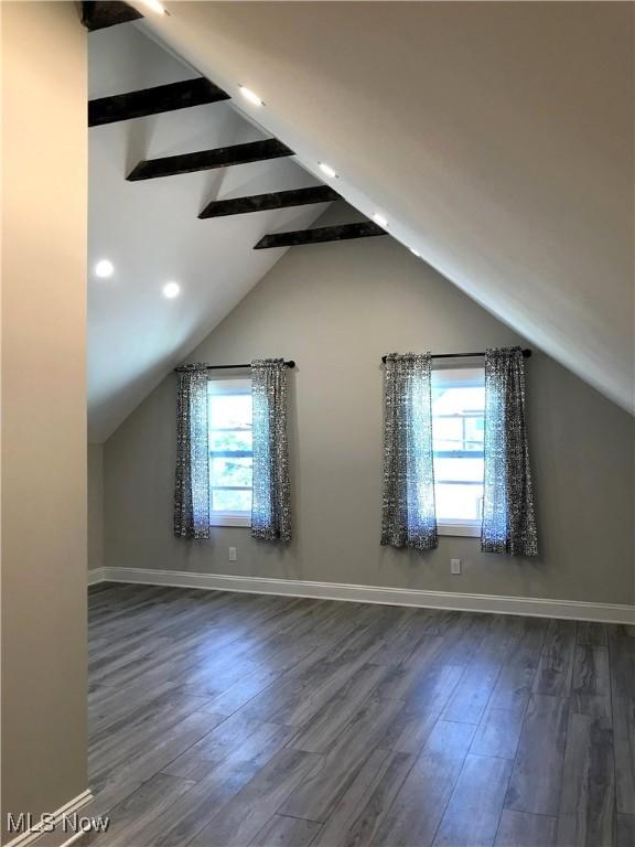 additional living space featuring dark hardwood / wood-style flooring and vaulted ceiling with beams