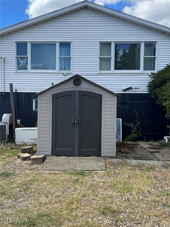 rear view of property featuring a storage unit