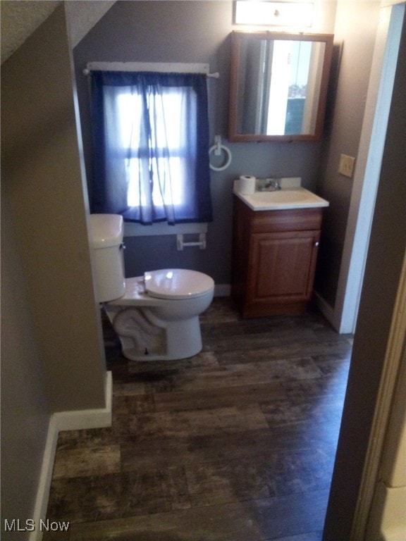 bathroom featuring vanity, hardwood / wood-style flooring, a healthy amount of sunlight, and toilet