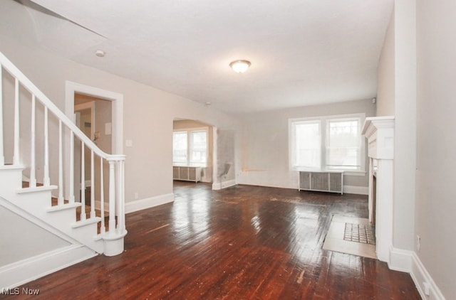 unfurnished living room featuring dark wood-type flooring and radiator heating unit