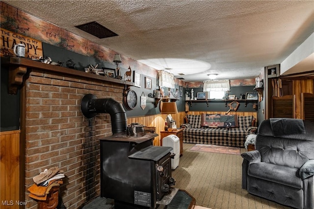 2207 Veto Rd, Vincent, OH 45784 - living area featuring a wainscoted wall, a wood stove, a textured ceiling, and wood walls