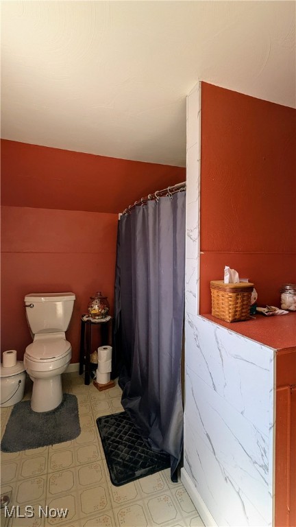 bathroom with curtained shower and toilet