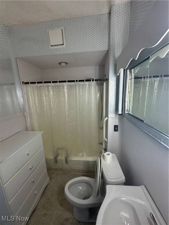 full bathroom featuring toilet, shower / bath combination with curtain, and sink