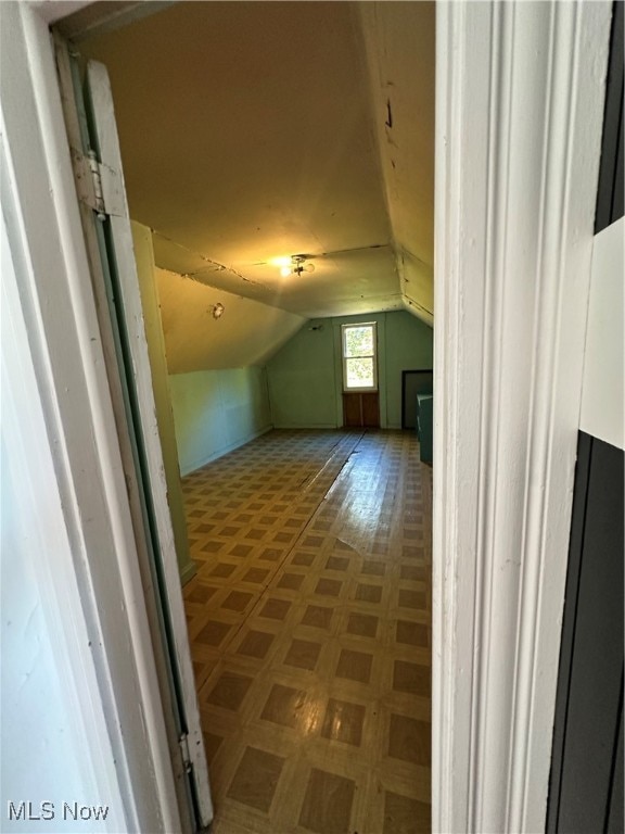 bonus room featuring parquet floors and vaulted ceiling