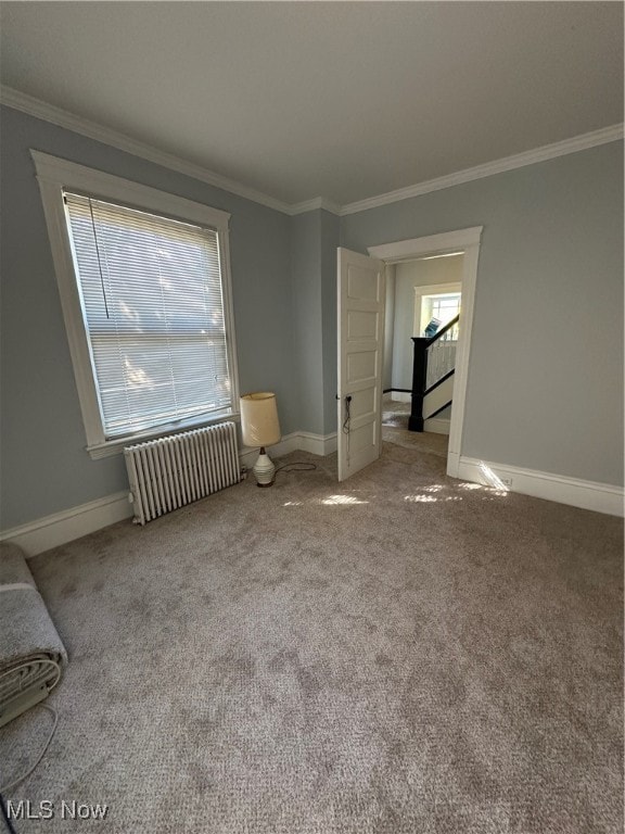 unfurnished living room featuring crown molding, carpet, and radiator