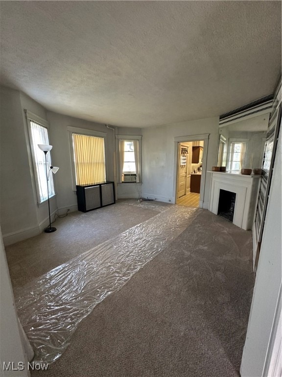 unfurnished living room featuring light carpet and a textured ceiling