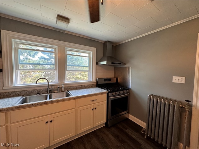 kitchen featuring white cabinets, wall chimney exhaust hood, gas range, radiator, and sink