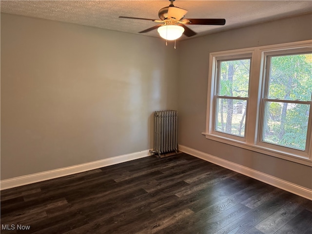 empty room featuring radiator heating unit, a textured ceiling, ceiling fan, and dark hardwood / wood-style flooring