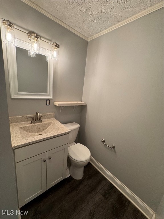 bathroom with vanity, ornamental molding, a textured ceiling, hardwood / wood-style flooring, and toilet