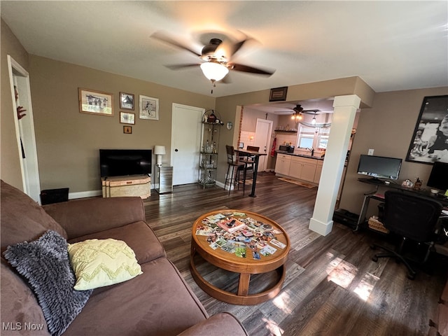 living room featuring decorative columns, dark hardwood / wood-style flooring, ceiling fan, and sink