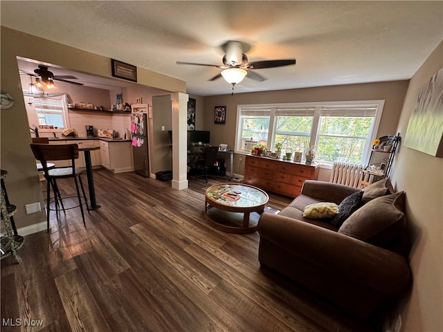 living room with a textured ceiling, ceiling fan, and dark hardwood / wood-style flooring