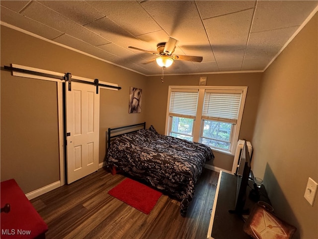 bedroom featuring crown molding, ceiling fan, dark hardwood / wood-style floors, and a barn door