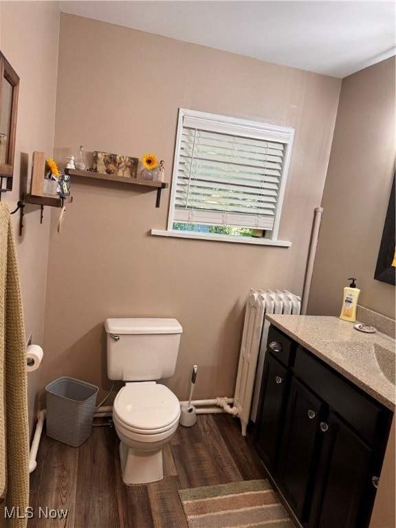 bathroom with wood-type flooring, vanity, toilet, and radiator heating unit