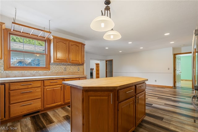 kitchen featuring hanging light fixtures, backsplash, a center island, dark hardwood / wood-style floors, and wood counters