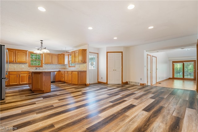 kitchen featuring pendant lighting, dark wood-type flooring, tasteful backsplash, and a center island