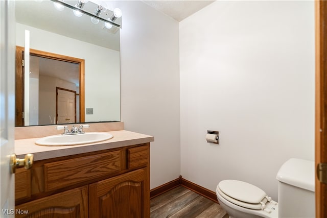 bathroom featuring wood-type flooring, vanity, and toilet