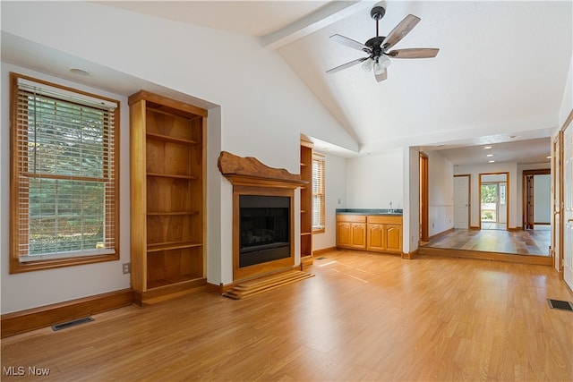 unfurnished living room with light hardwood / wood-style flooring, ceiling fan, lofted ceiling with beams, and sink