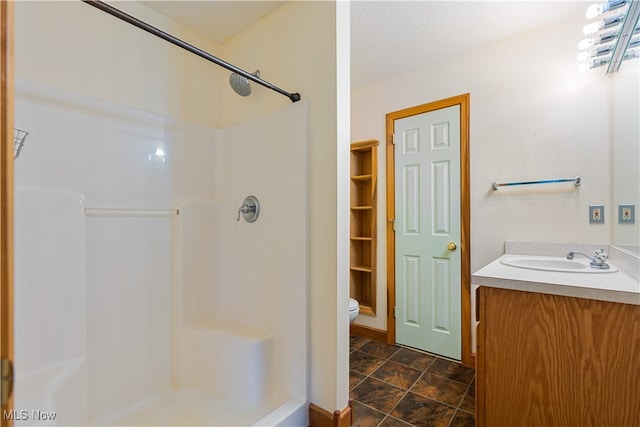 bathroom featuring a textured ceiling, a shower, vanity, and toilet