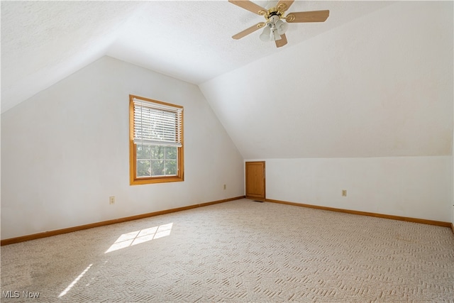 additional living space featuring a textured ceiling, lofted ceiling, carpet flooring, and ceiling fan