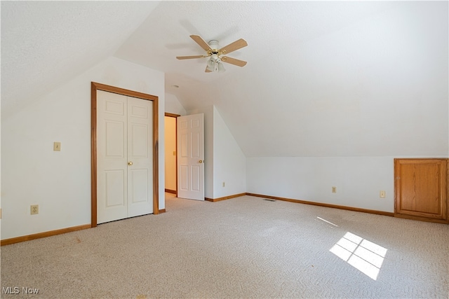 additional living space with ceiling fan, light colored carpet, a textured ceiling, and lofted ceiling