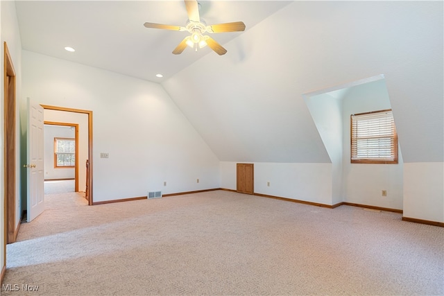 bonus room with vaulted ceiling, light carpet, and ceiling fan