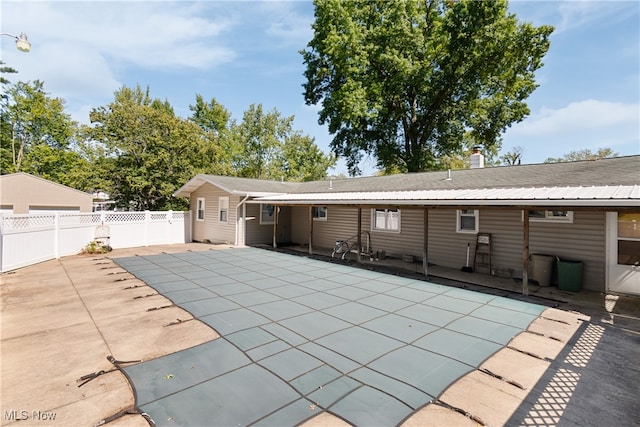 back of house featuring a covered pool and a patio area