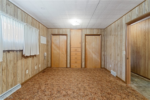 spare room featuring wooden walls and carpet flooring