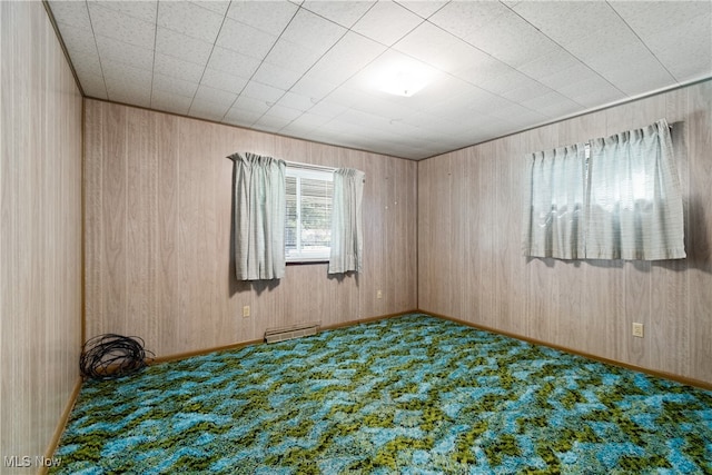 unfurnished room featuring wood walls and carpet