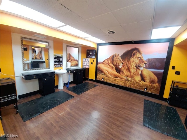 cinema room featuring sink, a drop ceiling, and dark hardwood / wood-style flooring