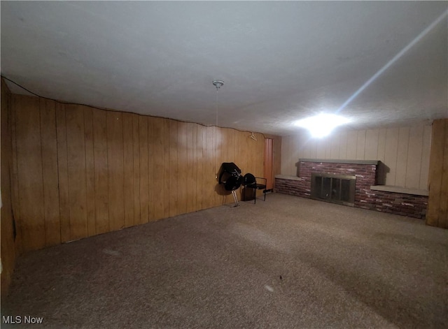 basement featuring wooden walls, a fireplace, and carpet flooring