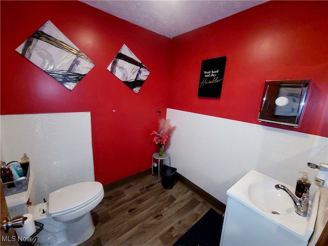 bathroom with tile walls, vanity, a textured ceiling, hardwood / wood-style flooring, and toilet