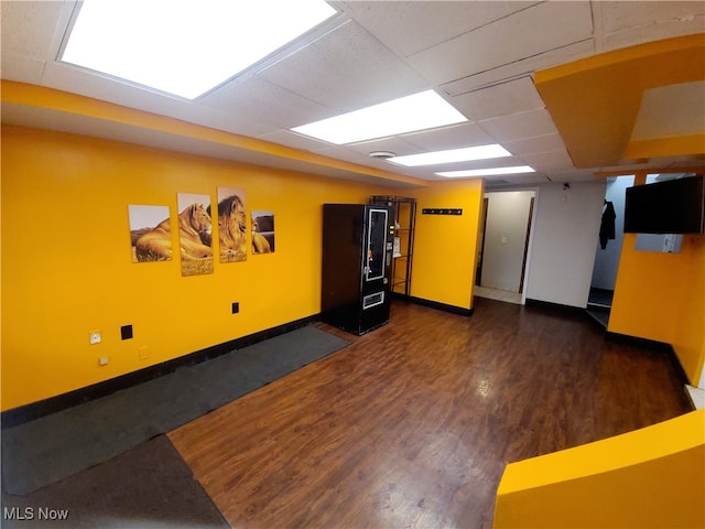 interior space with dark wood-type flooring and a paneled ceiling