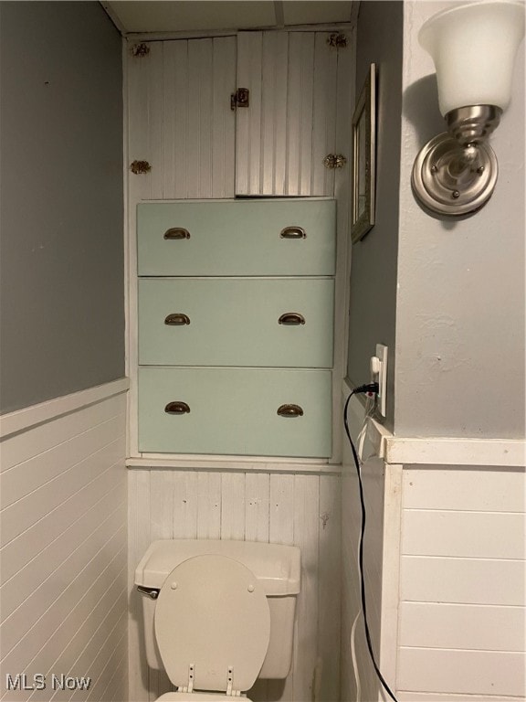 bathroom featuring tile walls and toilet