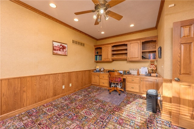 office featuring ceiling fan, wooden walls, built in desk, and crown molding