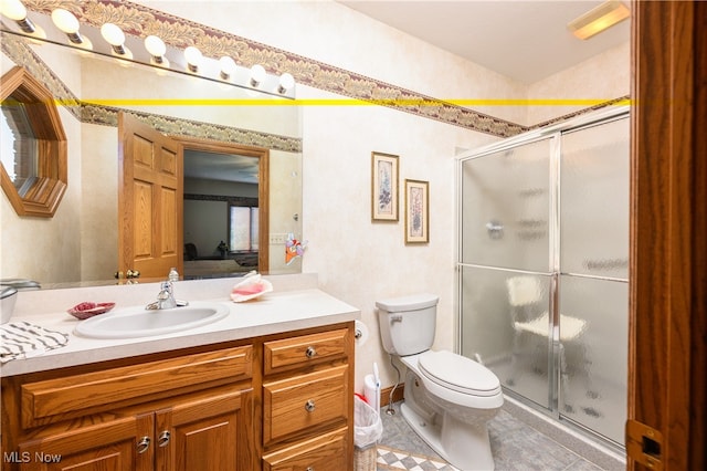 bathroom featuring vanity, toilet, tile patterned floors, and a shower with shower door